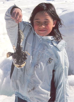 Inuit girl with fish at On Eagle's Wings camp